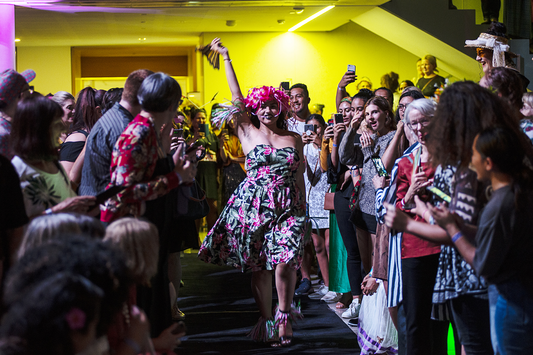 A person walking between a crowd of people as part of a Pacific Sisters Freestyle Whrock Action catwalk performance