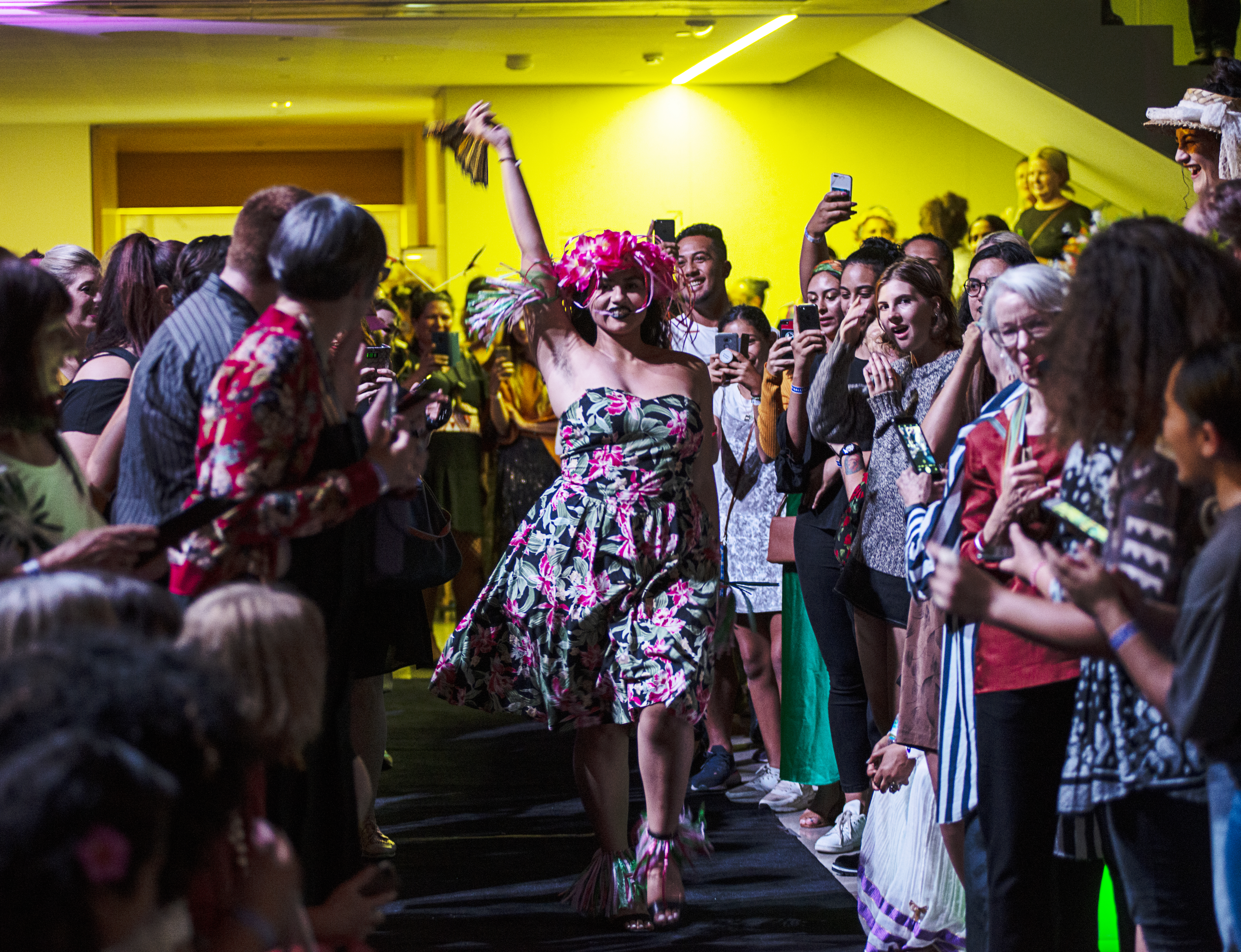 A person walking between a crowd of people as part of a Pacific Sisters Freestyle Whrock Action catwalk performance