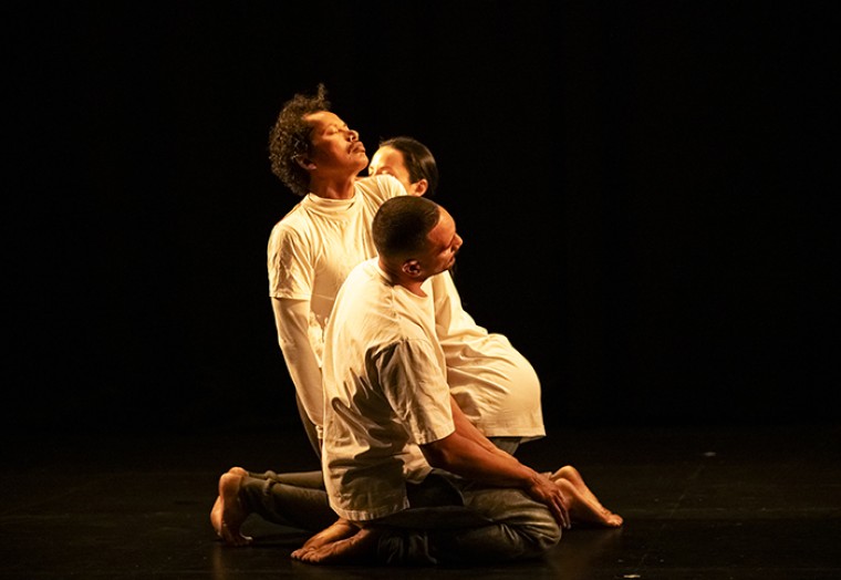 Three dancers part of the Bunyi Bunyi Bumi performance kneeling together 