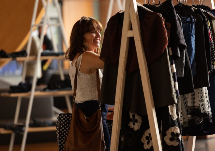 Image: A woman enjoys browsing through handmade clothing at a Style Swap market stall.